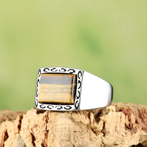 Détail macro d'une bague en titane pour homme avec œil de tigre sur écorce naturelle