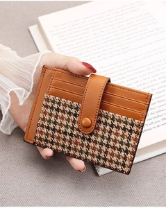 Detail of slim brown leather card holder with houndstooth fabric and snap closure
