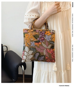 Detailed close-up of a linen handbag with floral embroidery and bamboo handle detail