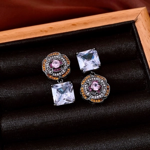 Macro shot of vintage asymmetrical flower earrings with colorful zircons on black velvet