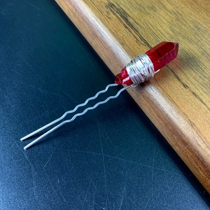 Macro shot of red crystal pillars woven with silver wire on a U-shaped hairpin