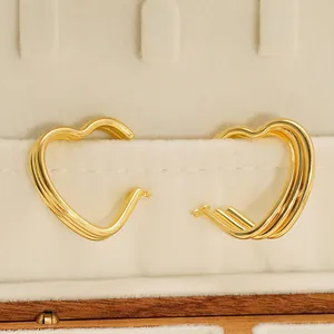 Boucles d'oreilles cœur multicouches chic en acier doré sur un plateau de bijoux en velours