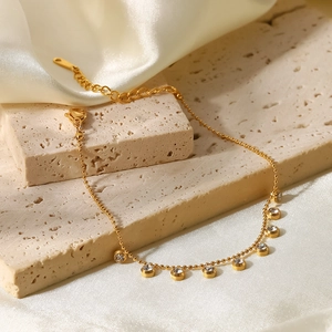 Detail of gold bead bracelet featuring sparkling bezel-set zircons on elegant fabric