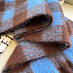 Close-up of blue and brown plaid scarf showing soft faux cashmere texture and tassels