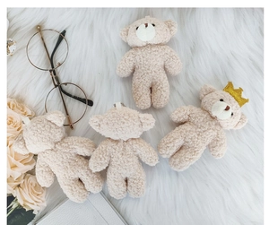 Detail of cream plush bear keychains with gold crown on soft white faux fur background