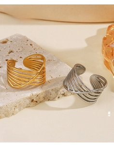Close-up of multilayered crisscross stainless steel rings in gold and silver finish