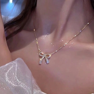 Detail of elegant bow pendant necklace with sparkling cubic zirconia on gold chain