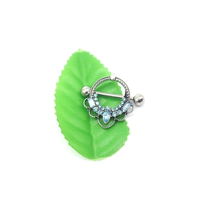 Vintage silver nipple ring with blue waterdrop crystals on green leaf background