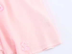 Détail d'une robe en tulle rose avec fleurs 3D faites à la main et accents de perles