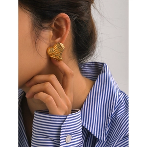 Detailed view of 18k gold heart earrings featuring unique woven texture on model