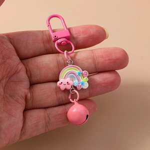 Pink rainbow and cloud keychain with metal bell and resin pendant held in hand