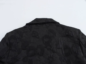 Detail of black jacquard floral pattern on shoulders and collar of a long winter coat