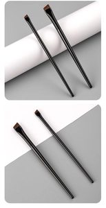 Close-up of dual black angled eyeliner and eyebrow brushes with brown synthetic bristles