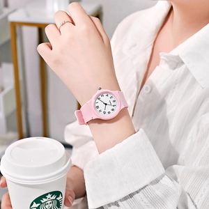 Pink quartz watch with silicone strap on wrist, featuring a clear white numerical dial