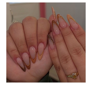 Detail of almond-shaped press-on nails with brown gradient and gold glitter French tips