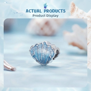 Close-up of S925 sterling silver shell charm with blue enamel on ocean background