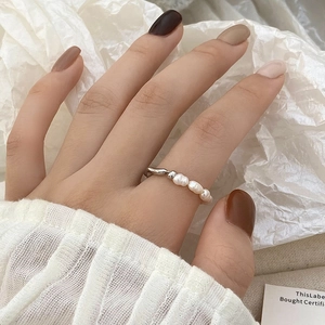 Detalle de un anillo minimalista con pequeñas perlas blancas y una cuenta de plata
