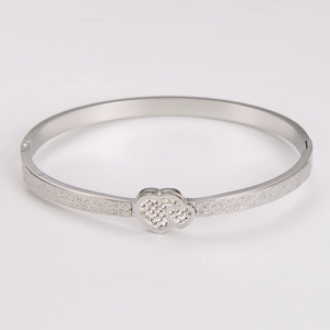 Detail shot of silver stainless steel bangle with frosted texture and dual crystal hearts