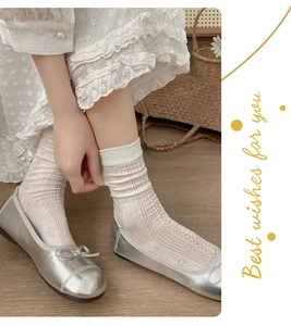 Close-up of white lace crew socks with hollow patterns and bow details on a model