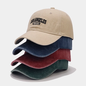 Detailed stack of vintage washed cotton baseball caps in khaki, navy, red and green colors