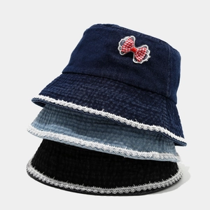 Detail showing stacked denim bucket hats with red plaid bows and white lace trim