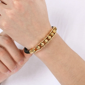 Detail of men's leather cord bracelet featuring gold skull beads and relief patterns