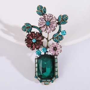 Detail of vintage Baroque vase brooch with pink flowers and a large green crystal