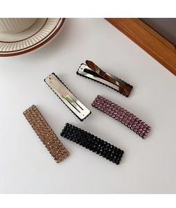 Detail view of five rhinestone hair clips in champagne, black and pink with metal base