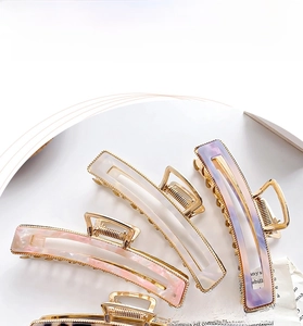 Close-up of elegant marble acetate hair claws in pastel colors with gold metal frames