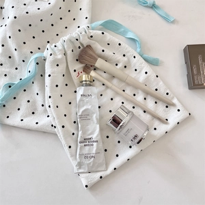 Polka dot drawstring bag for organizing makeup and skincare items in a soft lifestyle setting