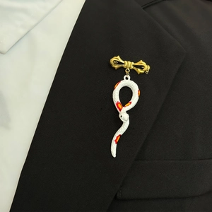 Vintage enamel snake brooch with golden bow knot pinned on a black suit lapel