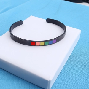 Macro detail of black matte C-shaped rainbow pride bracelet with colorful square inlays
