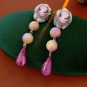 Detail of vintage teardrop earrings with purple resin relief and gradient beads