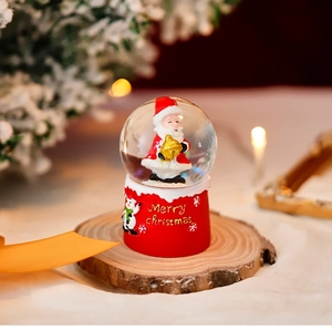 Luminous Christmas snow globe with Santa Claus figure on a red base and warm lights