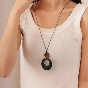 Macro detail of geometric resin pendant necklace with wood grain texture and black ring