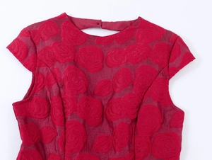 Détail du tissu jacquard floral rouge sur la robe sans manches dos nu à col rond