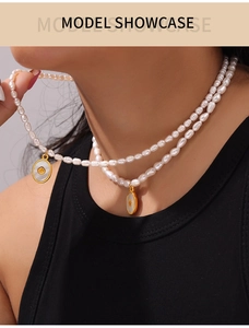 Model wearing double-layer freshwater pearl necklace with gold shell embossed pendants