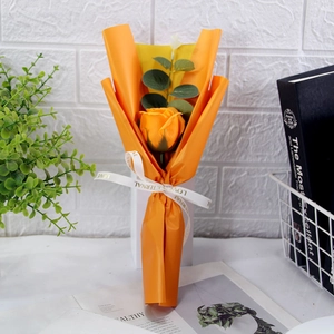 Close-up of a single yellow soap rose wrapped in orange paper with a LOVE ETERNAL ribbon