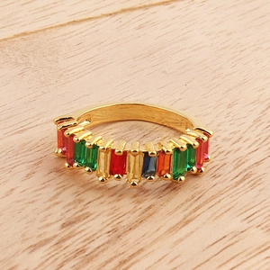 Detailed top view of golden ring with multi-colored baguette-cut crystals on wood