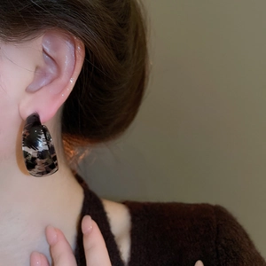 Detailed close-up of model wearing leopard resin C-shape hoop earrings in coffee and black