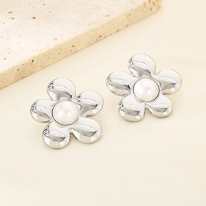 Gros plan détaillé de boucles d'oreilles fleurs argentées avec perle sur tissu beige