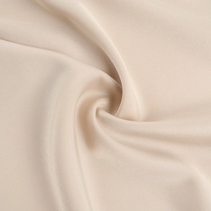 Vue macro détaillée montrant la texture en soie champagne lisse et le drapé doux de la robe