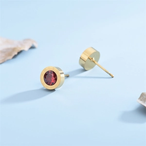 Minimalist gold titanium stud earrings featuring Roman numerals and a red crystal center