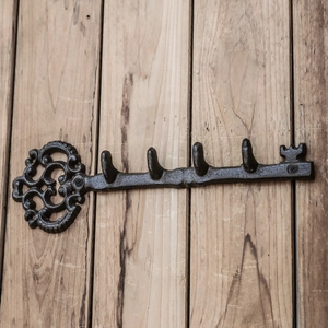 Vintage key-shaped cast iron wall hook rack with 5 hooks on a wooden background