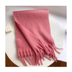 Close-up of a pink mohair scarf with fringe tassels on a minimalist white table
