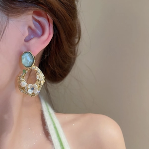 Detail of vintage gold flower earrings with teal stones and pearls on model