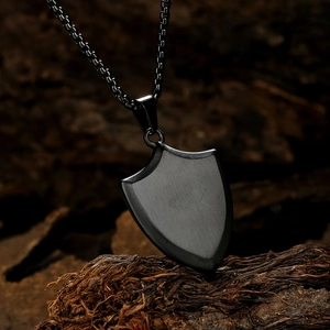 Black stainless steel triangle shield pendant necklace on dark wood background