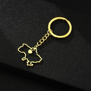Close-up of golden Ukraine map pendant with a small heart on a black textured surface