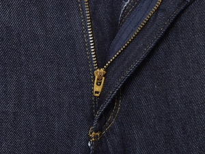 Gros plan macro de la fermeture éclair YKK en métal et de la texture du denim bleu foncé