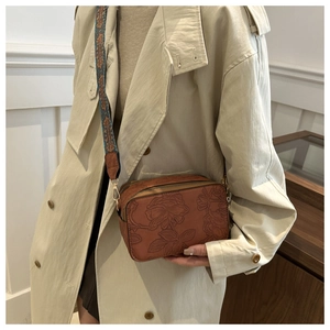 Caramel brown camera bag with embossed floral details and a bohemian wide strap